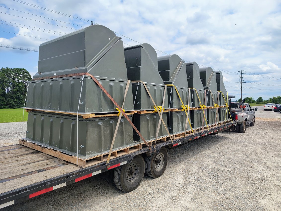 A gooseneck flatbed loaded with large fabricated steel structures, strapped and blocked for an oversize move